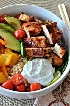 a white bowl filled with chicken, rice and veggies