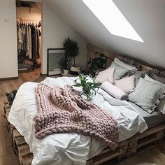 a bed made up with blankets and pillows on top of it in a loft space