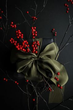 a bow tied to a tree with red berries