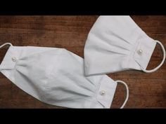 two white cloth face masks sitting on top of a wooden table