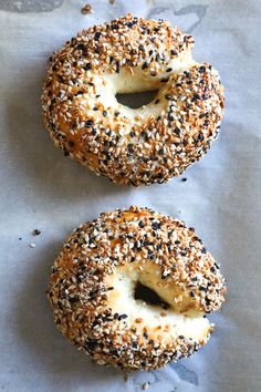 two bagels with sesame seeds are on a piece of wax paper