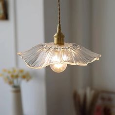 a light fixture hanging from a ceiling in a room with white walls and flowers on the table