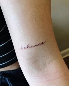 a woman's arm with the word balance tattooed on her left side ribcage