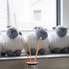 three knitted sheep sitting next to each other on a window sill