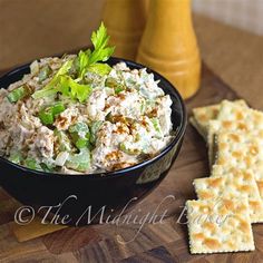 a black bowl filled with food next to crackers