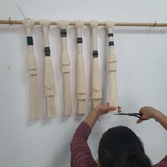 a woman is using scissors to cut the ends of wooden tassels on a wall