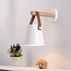 a white lamp hanging from the side of a wall next to a potted plant