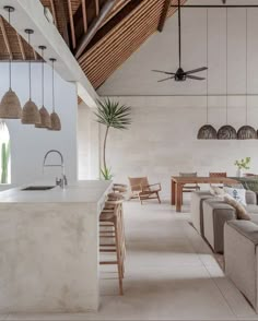 a living room filled with furniture next to a kitchen and dining area in front of a ceiling fan