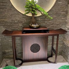 a bonsai tree is placed on top of a wooden table in front of a mirror