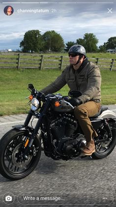 a man riding on the back of a motorcycle down a street next to a field