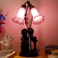 a lamp that is sitting on top of a table next to a vase with flowers