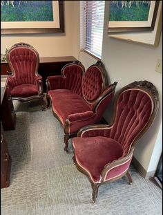 three red velvet chairs sitting next to each other in front of a painting on the wall