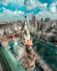 a woman hanging upside down from the top of a building