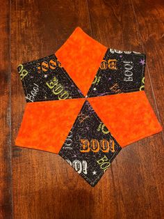 an orange and black patchwork piece on top of a wooden floor