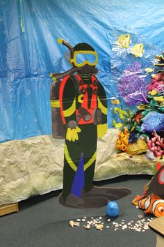 a paper cut out of a scuba diver in front of an ocean scene with fish and corals