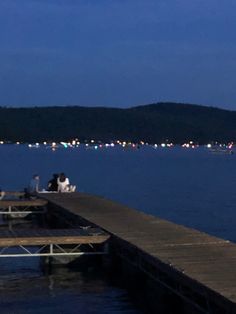 two people sitting on a dock at night