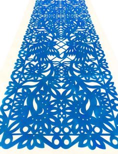 an intricately designed blue table runner with circles and leaves on the top, in front of a white background