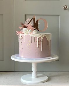 a pink cake with white icing and flowers on top is displayed in front of a door