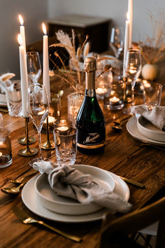 the table is set with candles, plates and wine bottles for dinner guests to enjoy