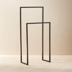 two black metal frames sitting on top of a white floor next to each other in front of a beige wall