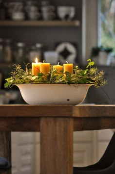 a bowl filled with candles sitting on top of a wooden table