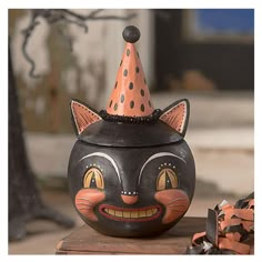 a black cat with a polka dot hat on it's head sitting next to some pumpkins