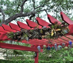 a red bench with plants hanging from it's sides