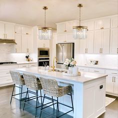 a kitchen with white cabinets and an island in front of the countertop is surrounded by wicker bar stools