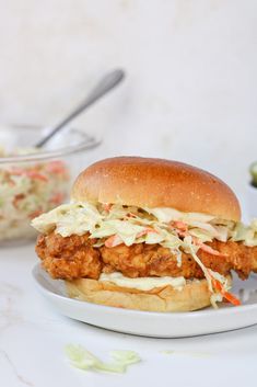 a chicken sandwich on a plate with cole slaw