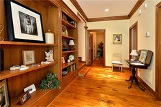 a room with wooden shelves and pictures on the wall next to a desk in front of an open door