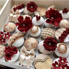 a box filled with lots of decorated cupcakes on top of a table next to each other