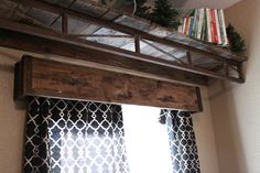 a shelf with books on top of it above a window