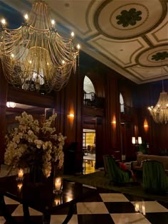 the chandelier is hanging from the ceiling in this elegant hotel lobby with black and white checkered flooring