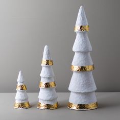 three white and gold decorated christmas trees sitting on top of a table next to each other