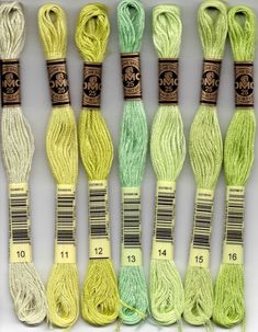 several skeins of yarn are lined up on a white surface, one is green and the other is yellow