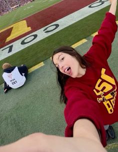 a girl in a red shirt is on the ground with her arms up and hands raised