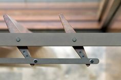 two metal brackets are attached to the side of a wooden structure with holes in it