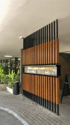 the entrance to an office building with wooden slats on it's sides and plants in pots