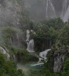 the waterfall is surrounded by lush green trees and foggy skies in the distance, as well as water cascading down the sides