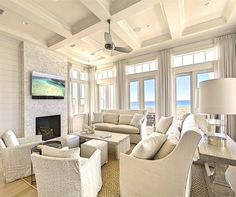 a living room filled with furniture and a fire place in front of a window overlooking the ocean