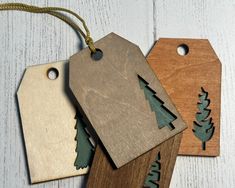 three wooden tags with trees on them are hanging from string and two have wood tags attached to the strings