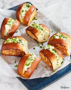 several hot dogs on buns with green toppings