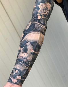 a man's arm with a skull and roses tattoo on it