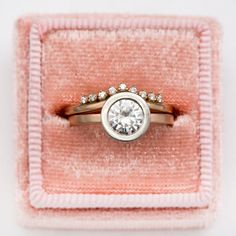 an engagement ring in a pink velvet box with white stones on the top and bottom