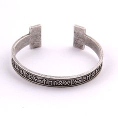 a silver bracelet with greek writing and symbols on the side, in front of a white background