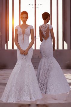 two women in wedding gowns standing next to each other with their backs turned towards the camera