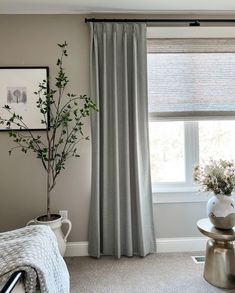 a living room with a couch, chair and window covered in gray drapes next to a potted plant