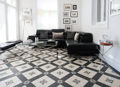 a living room with black and white flooring and pictures on the wall above it