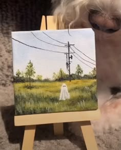 a dog is looking at an easel with a painting on it's side