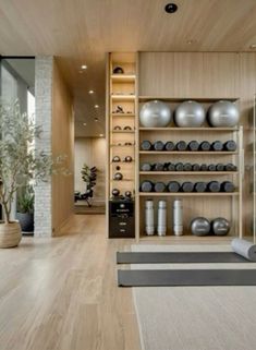 there is a yoga mat on the floor in front of shelves with exercise balls and dumbbells